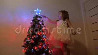 孩子在节日<strong>树</strong>上检查<strong>一颗</strong>圣诞星。 小女孩在孩子们的房间里靠近圣诞<strong>树</strong>`玩耍